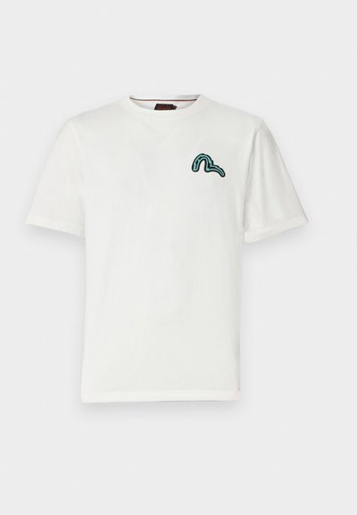Camiseta de algodón blanca de manga corta, con un bordado en forma de serpiente turquesa en el lado izquierdo del pecho. Diseño clásico de cuello redondo.