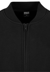 Veste noire zippée avec col côtelé, dotée d'une fermeture éclair centrale et d'une étiquette Urban Classics à l'intérieur du col.