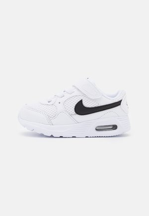Biały dziecięcy sneaker z czarnym logo Nike, cholewką z siateczki, paskiem na rzep i widoczną podeszwą z poduszką powietrzną na białym tle.