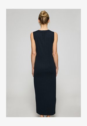 Navy ribbed maxi dress with sleeveless design, fitted silhouette, and subtle texture. Long length reaching ankles, simple neckline.