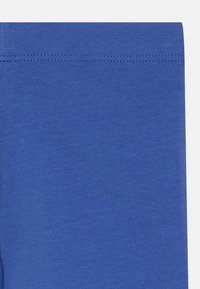 Kék leggings puha, rugalmas anyagból, sima felülettel. Párnázott derékpánttal és varrás nélküli kialakítással a kényelem érdekében.