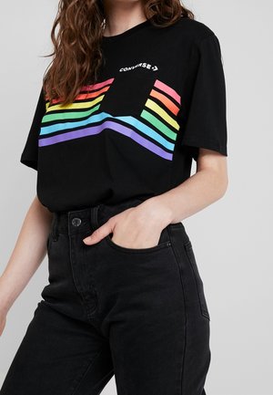 Camiseta negra de algodón con diseño de franjas arcoíris multicolor en el pecho, con un pequeño bolsillo frontal y corte relajado.