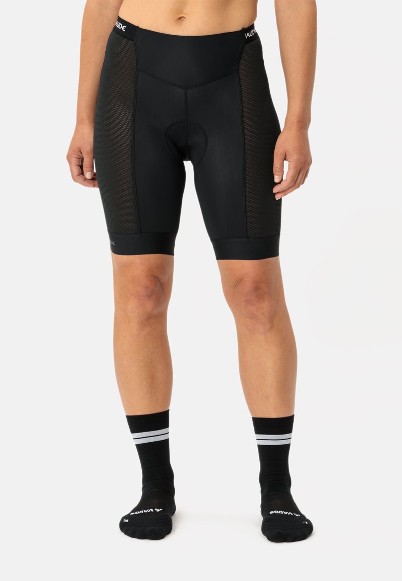 Pantaloni da ciclismo neri con pannelli laterali in mesh, dotati di un fondello imbottito per il comfort. Indossati con calzini neri con strisce bianche.