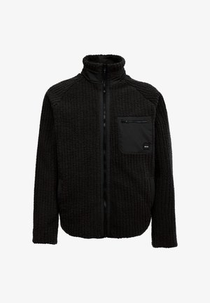 Schwarze Fleecejacke mit einer strukturierten Körperoberfläche, hohem Kragen, durchgehendem Reißverschluss und einer Brusttasche mit Reißverschluss. Akzentuiert mit schwarzen Details.