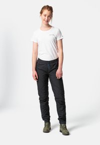 Pantalons noirs isolés avec un motif en losange, taille élastique avec cordon de serrage et poches latérales ; associés à une chemise blanche à manches courtes.