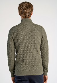 Kaki stickad tröja med ett strukturerat diamantmönster, hög krage, ribbade ärmslut och nederkant. Tillverkad av ett mjukt, tjockt material.