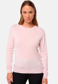 Pull en tricot rose clair à manches longues et col rond. Le tissu semble doux et légèrement texturé, avec des poignets et un ourlet côtelés.