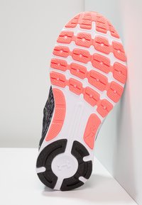 Suola di scarpa da corsa nera con un motivo testurizzato, accenti rosa vivaci e segmenti bianchi, progettata per trazione e durata.