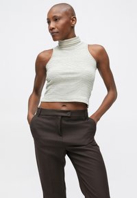 Csíkos bordázott crop top világosszürke és sötétszürke színben, magas nyakkal és ujjatlan kivitelben, sötétbarna, szabott nadrággal párosítva.
