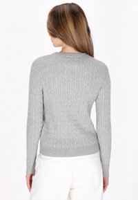 Grauer gerippter Pullover mit enganliegender Silhouette, langen Ärmeln und rundem Halsausschnitt; strukturierter Strickmuster und subtile Saumdetails.