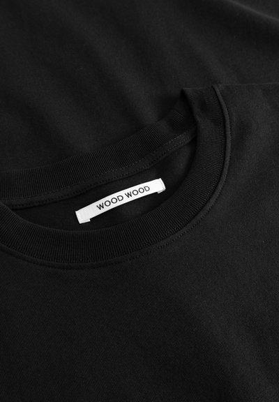 T-shirt de algodão preta com decote redondo, apresentando uma gola canelada e uma etiqueta de tecido branca com "WOOD WOOD" impresso a preto.