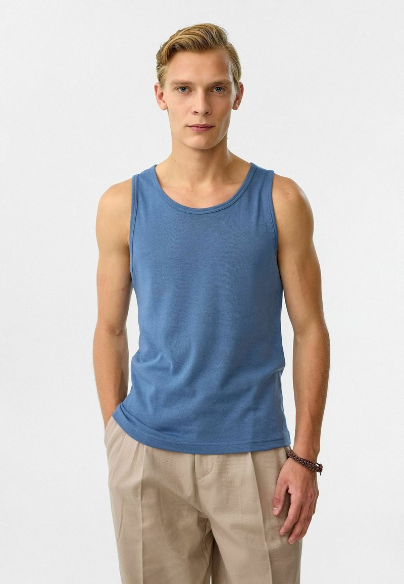 Blauwe katoenen tanktop met een ronde hals, nauwsluitend ontwerp en een soepele textuur, gecombineerd met lichtbeige broeken.