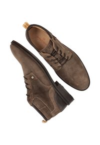 Bruine suède schoenen met een gestructureerde afwerking, ronde neus, vijf veteroogjes en een contrasterend materiaal aan de zijkant. Voorzien van een lussen aan de hiel.