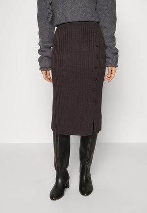 Mørkebrun ribstrikket knælængde nederdel med sidesømknapper og slids, kombineret med sorte hælede støvler og grå langærmet sweater.