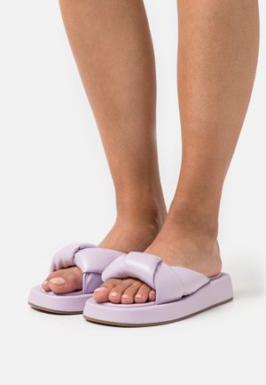 Sandales à enfiler violettes avec une large bride nouée en matière synthétique lisse, dotées d'une semelle épaisse et d'un design à bout ouvert.