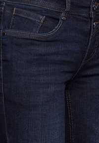 Mörkblå denimjeans med en klassisk femficksdesign, subtila sömnadsdetaljer och en mjuk textur.