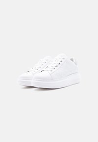 Λευκά αθλητικά παπούτσια με ομαλή επιφάνεια, υφασμένα πλευρικά πάνελ, στρογγυλεμένη μύτη και επίπεδη ελαστική σόλα με διακριτική σήμανση και σχέδιο με κορδόνια.