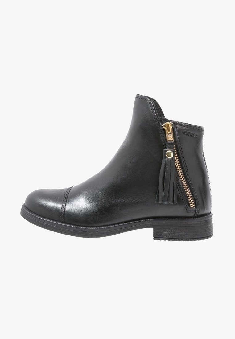 Bottine en cuir noir avec petit talon, fermeture éclair latérale avec pompon et détail de coutures visibles sur le bout et le talon.