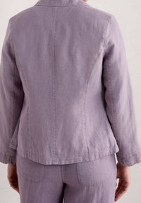 Blazer en lin lavande clair à coupe ajustée, avec un col cranté et des manches longues. Tissu texturé et détails de couture minimalistes.