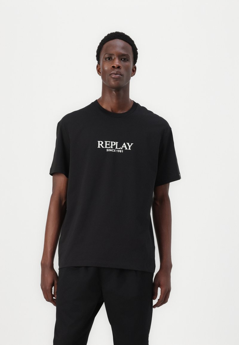 Must musta t-särk lühikeste varrukatega, millel on ees valge "REPLAY SINCE 1981" logo, ümmargune kaelus ja mugav lõige.