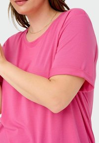 Rožinė trumpomis rankovėmis marškinėliai, pagaminti iš lygaus audinio, su apvaliu iškirpimu ir sukritusiais rankogaliais. Paprastas dizainas, lengvas ir laisvas fasonas.