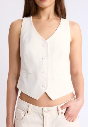 Gilet bianco senza maniche con bottoni, indossato da una persona con una mano nella tasca dei pantaloni bianchi abbinati, visibile dalle spalle fino alla vita media.