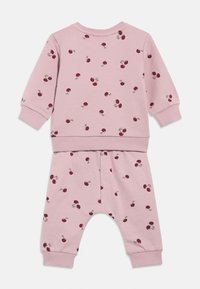Ensemble sweat-shirt à manches longues et pantalons roses avec motifs de cerises rouges, poignets et taille côtelés, conçu pour les nourrissons ou les tout-petits.