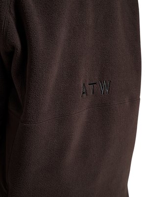 Donkerbruin fleece stof met zwarte geborduurde letters "ATW" gecentreerd op het zichtbare gebied, met textuur- en stiksel details.