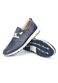 Námořnické kožené boty s hladkým povrchem, kulatou špičkou, krémovými gumovými podrážkami a béžovými šňůrkami. Podpisová značka na boku.