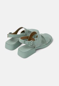 Mintvihreät sandaalit, joissa on nupukkinahkainen pinta, leveät ristikkäiset hihnat ja neliömäinen lohko korko. Varustettu säädettävällä nilkkahihnalla, jossa on solki.