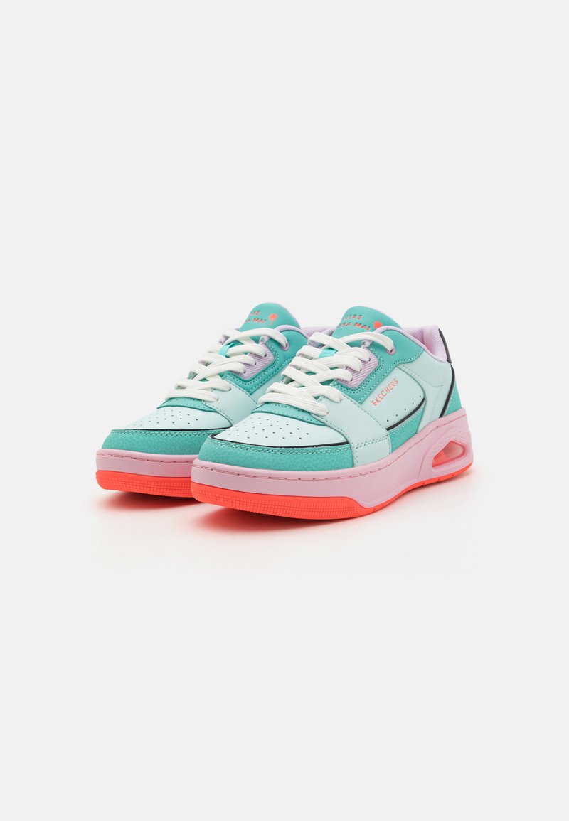 Des chaussures de sport turquoise et roses avec un bout perforé, des lacets blancs et une semelle rembourrée avec une unité d'air visible.