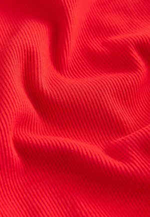 Jasně červená látka s vlnitou strukturou, která vykazuje hladké záhyby a sklady, zdůrazňující její elastické a lehké vlastnosti.