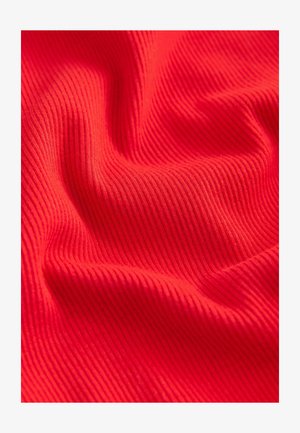 Svetlo rdeča tkanina z rebrasto teksturo, ki prikazuje gladke gube in pregibe, kar poudarja njene elastične in lahke lastnosti.