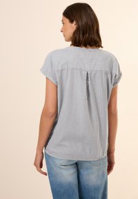 Striped short-sleeve blouse with a relaxed fit, featuring a back pleat and soft, lightweight fabric in navy and white colors.