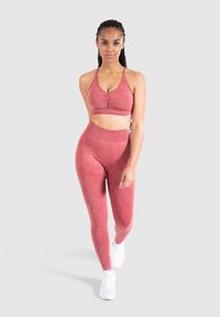 Bordeaux sportbeha met ruching aan de voorkant, gecombineerd met hoge taille bordeaux leggings. De stof lijkt zacht met een lichte glans; gelijkmatige kleur door het geheel.