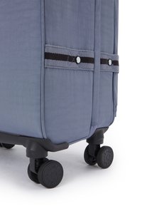 Soft-sided grey suitcase with a textured finish, featuring black wheels and fabric straps with black and white accents.