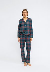 Károvaný pyžamový set v tmavozelenej farbe, ktorý má červené a modré pruhy; blúzka sa zapína na gombíky a má golier, nohavice s elastickým pásom.