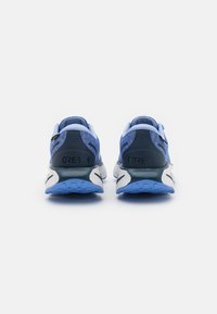 Zilā sporta apavi ar sietveida un sintētisku augšdaļu, ar baltu zoli, izteiktu papēža atbalstu un "GORE-TEX" zīmola logo aizmugurē.