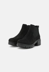 Bottines en daim noir avec des panneaux latéraux élastiques, une semelle épaisse et un minimum de détails en métal. La texture est lisse avec une finition mate.
