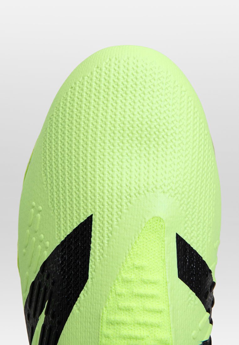 Parte superior de zapatilla deportiva en un brillante color verde lima con material de punto texturizado, que presenta patrones de acento negro prominentes y un diseño de punta redondeada y suave.