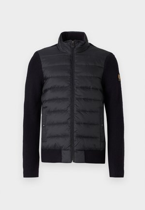 Black zip-up jacket with quilted front panel and knitted sleeves, featuring side pockets and a small logo patch on the left arm.