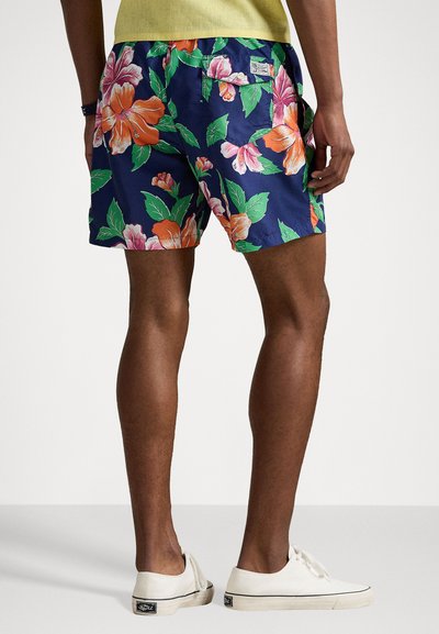 Floral swim shorts in navy blue with large orange and pink flowers, featuring a back pocket and side slits for ease of movement.