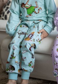 Ljusblå pyjamasbyxor med lekfulla illustrationer av djur och gårdsscener. Mjukt tyg med elastiska avslut; matchande långärmad topp synlig ovanför.