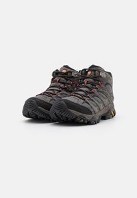 Szare buty trekkingowe wykonane z siateczki i gumowych materiałów, z czarnymi akcentami i czerwonymi sznurówkami. Głęboka podeszwa zapewniająca lepszą przyczepność.