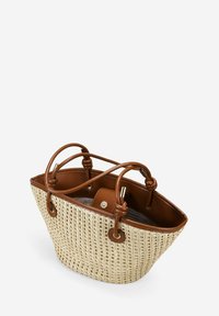 Bolso de paja tejido con acentos de cuero marrón, dos asas superiores y un interior espacioso. Presenta una textura suave y una forma redondeada.