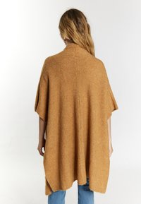 Kamel-färgad, löst sittande stickad poncho med hög hals, korta ärmar och en avslappnad silhuett, med en mjuk textur och sidoklipp.
