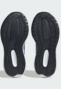 Suola in gomma nera con modelli di grip testurizzati; la parte intermedia presenta una sezione in schiuma bianca contrassegnata "CLOUDFOAM". Progettata per trazione e comfort.