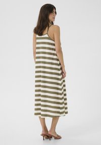 Abito maxi con strisce orizzontali verde oliva e crema. Design senza maniche, vestibilità comoda, realizzato in tessuto morbido, con una superficie leggermente texturizzata.