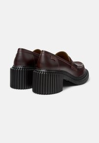 Brązowe skórzane buty z okrągłym noskiem, z grubym czarnym, żłobionym obcasem i subtelnymi detalami przeszyć. Logo na obcasie.