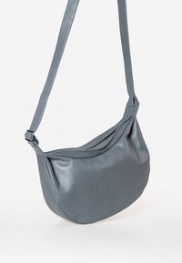 Oversized hobo tas van soepel blauw leer met een gebogen vorm en een enkele verstelbare schouderband. Gladde textuur met een minimalistisch ontwerp.